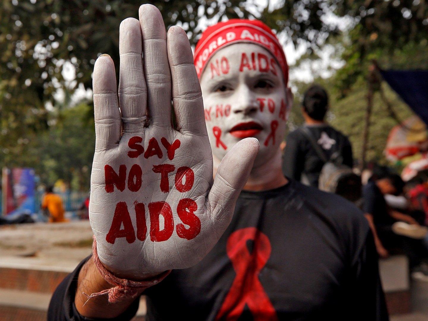 صورة لأحد المشاركين في حملة التوعية بمرض الإيدز بالهند طالياً وجهه بالأبيض وكاتباً على يده قل لا للإيدز وعلى وجهه نفس العبارة وشعار مرض الإيدز الاحمر.